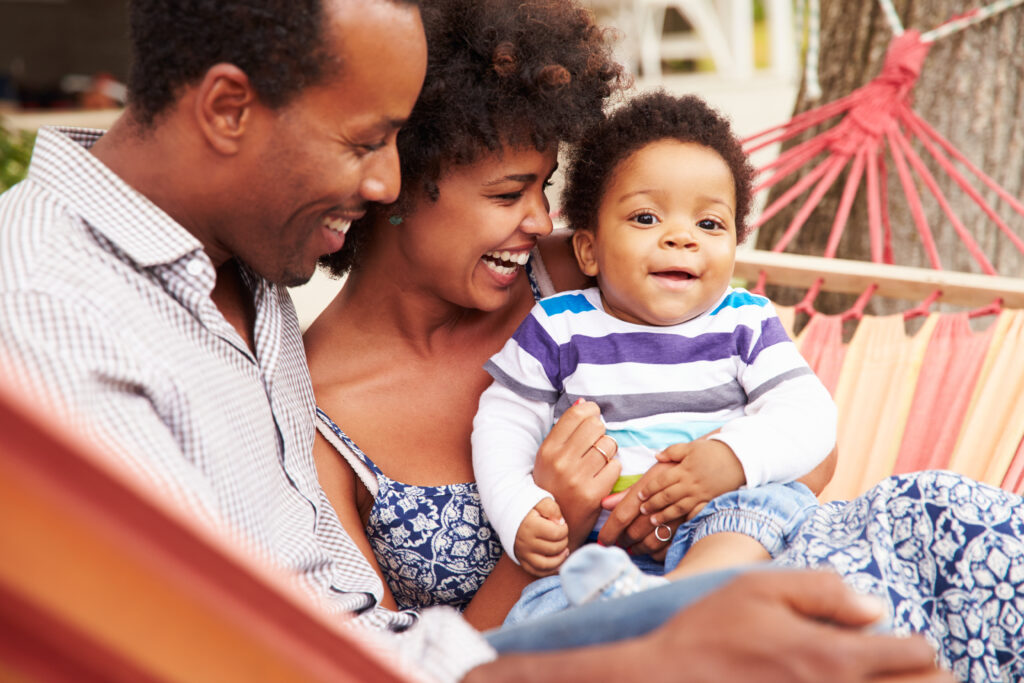 Happy coupleÿwith young child sitting in a hammock