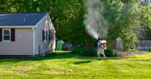 Mosquito Enemy technician treating shaded shrubs near a backyard deck in Massachusetts.