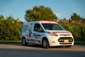 Branded Mosquito Enemy service van parked beside tall green vegetation on a sunny service day
